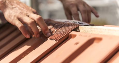 Roofer applying Alu-Grip Rol ridge and hip roll on ridge with bare hands