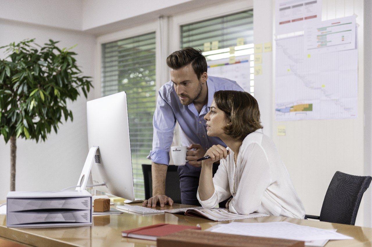 Male and female project manager collaborating in front of computer screen at office