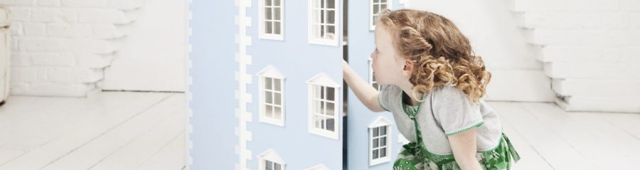 Girl sitting on the floor playing with doll house in attic loft
