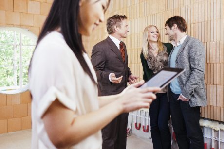 Architect showing a couple around their new built home. Woman with tablet passing by in front
